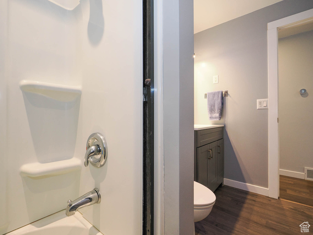 Full bathroom featuring hardwood / wood-style floors, vanity, tub / shower combination, and toilet