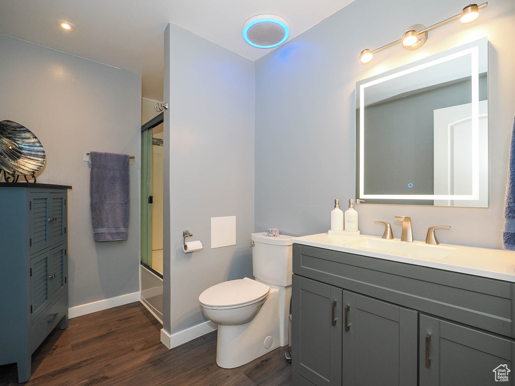 Full bathroom featuring vanity, toilet, hardwood / wood-style flooring, and enclosed tub / shower combo