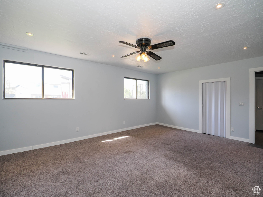 Spare room with a textured ceiling, ceiling fan, and carpet flooring