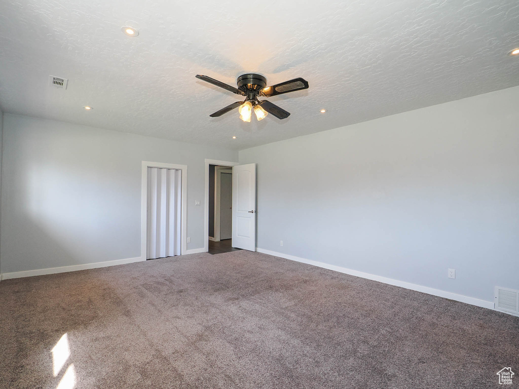 Spare room featuring carpet flooring, ceiling fan, and a textured ceiling