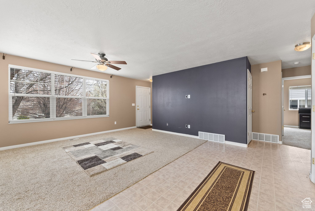 Interior space with a healthy amount of sunlight, ceiling fan, and light tile floors