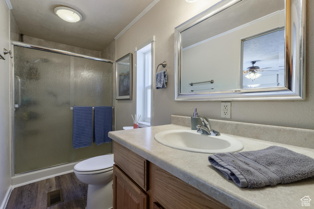 Bathroom with vanity, hardwood / wood-style floors, a shower with shower door, toilet, and ceiling fan