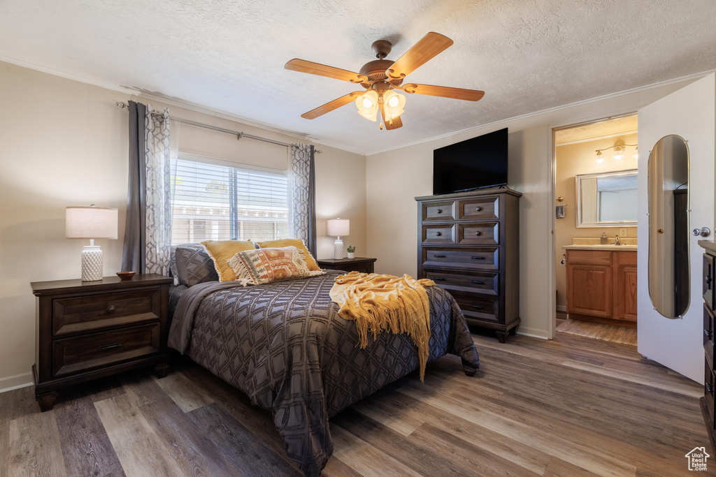 Bedroom featuring crown molding, ensuite bath, dark wood-type flooring, ceiling fan, and a textured ceiling