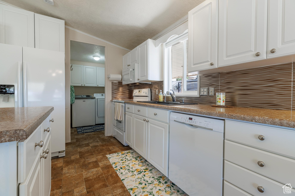 Kitchen featuring white appliances, white cabinetry, washing machine and clothes dryer, tasteful backsplash, and dark tile flooring