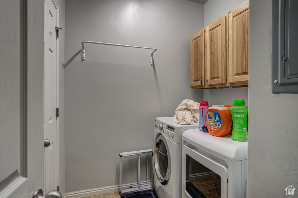 Clothes washing area featuring cabinets, tile floors, and washing machine and clothes dryer
