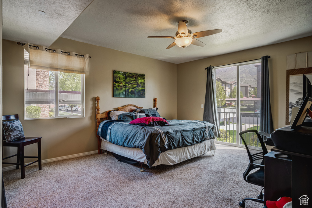 Carpeted bedroom with ceiling fan, access to outside, and a textured ceiling