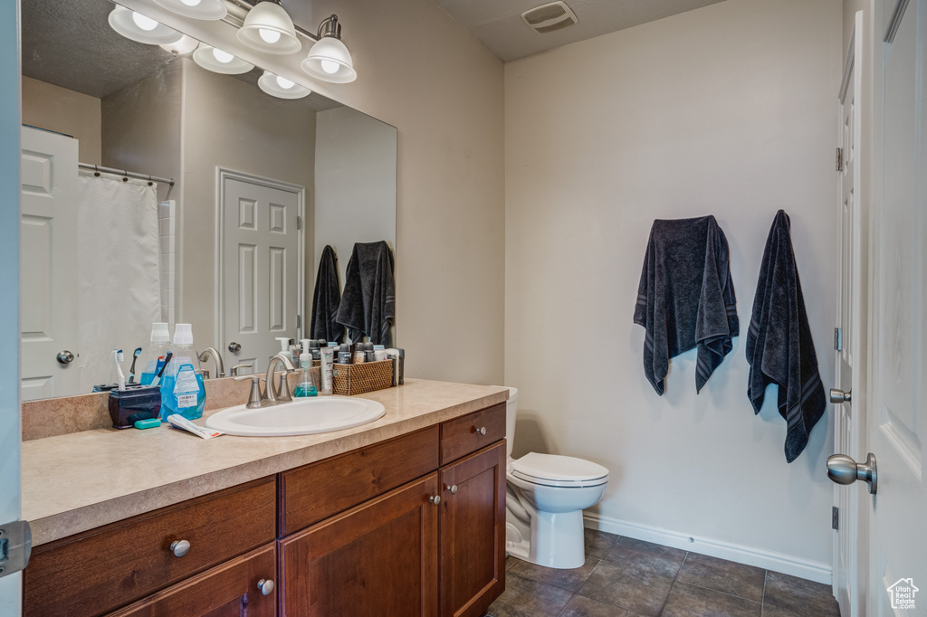 Bathroom featuring vanity, tile floors, and toilet