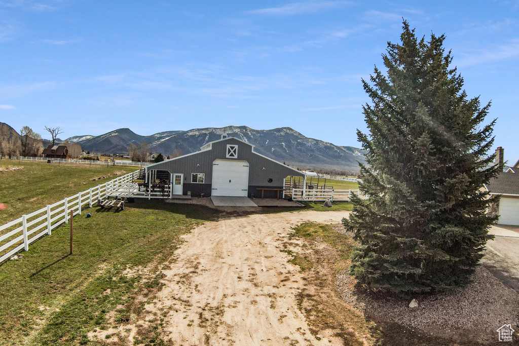 View of front facade featuring a garage, a mountain view, a front yard, and a rural view