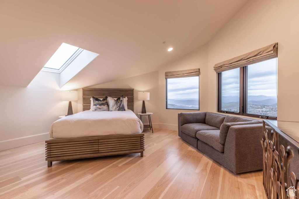 Bedroom with light hardwood / wood-style flooring, a mountain view, and lofted ceiling with skylight