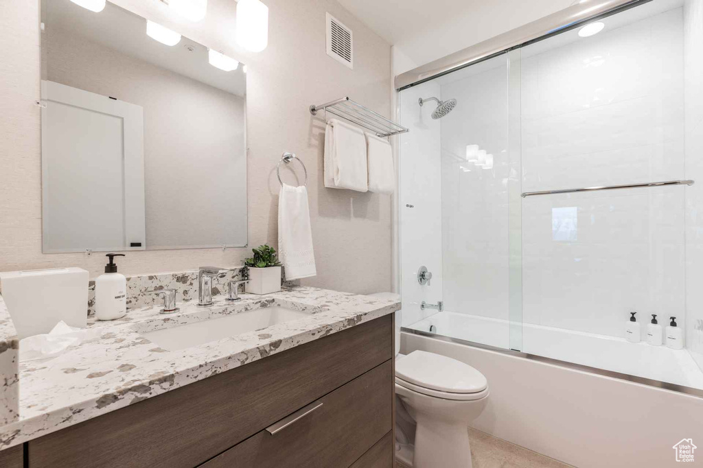 Full bathroom with vanity, toilet, and bath / shower combo with glass door