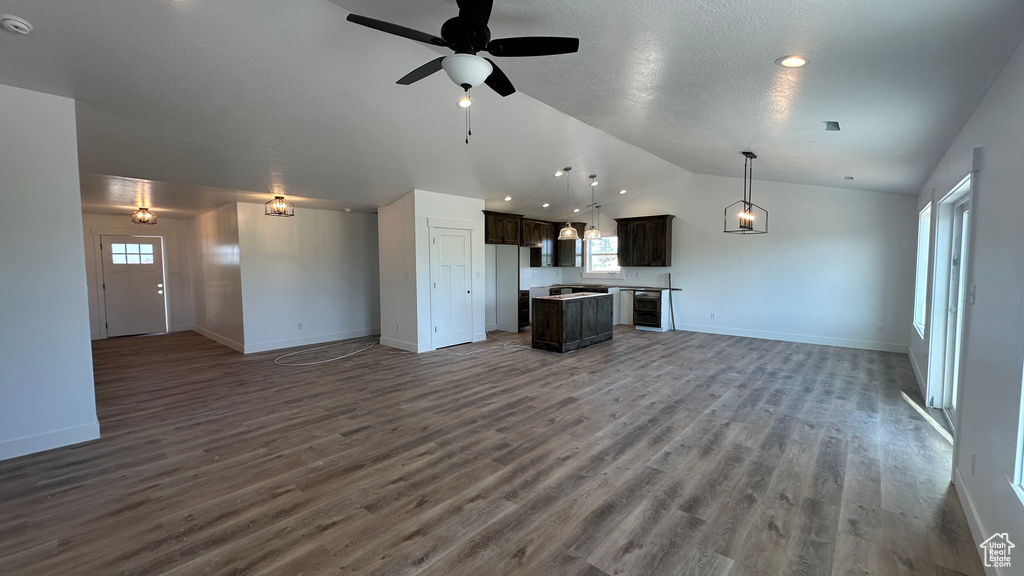 Unfurnished living room with dark wood-type flooring, ceiling fan, and lofted ceiling