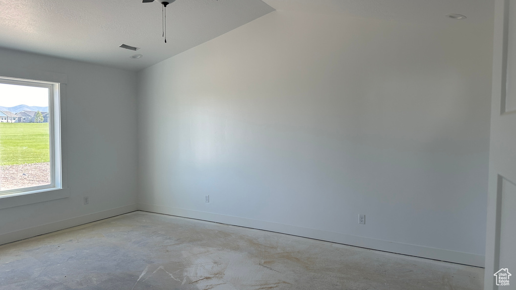 Unfurnished room featuring a healthy amount of sunlight, lofted ceiling, and concrete flooring