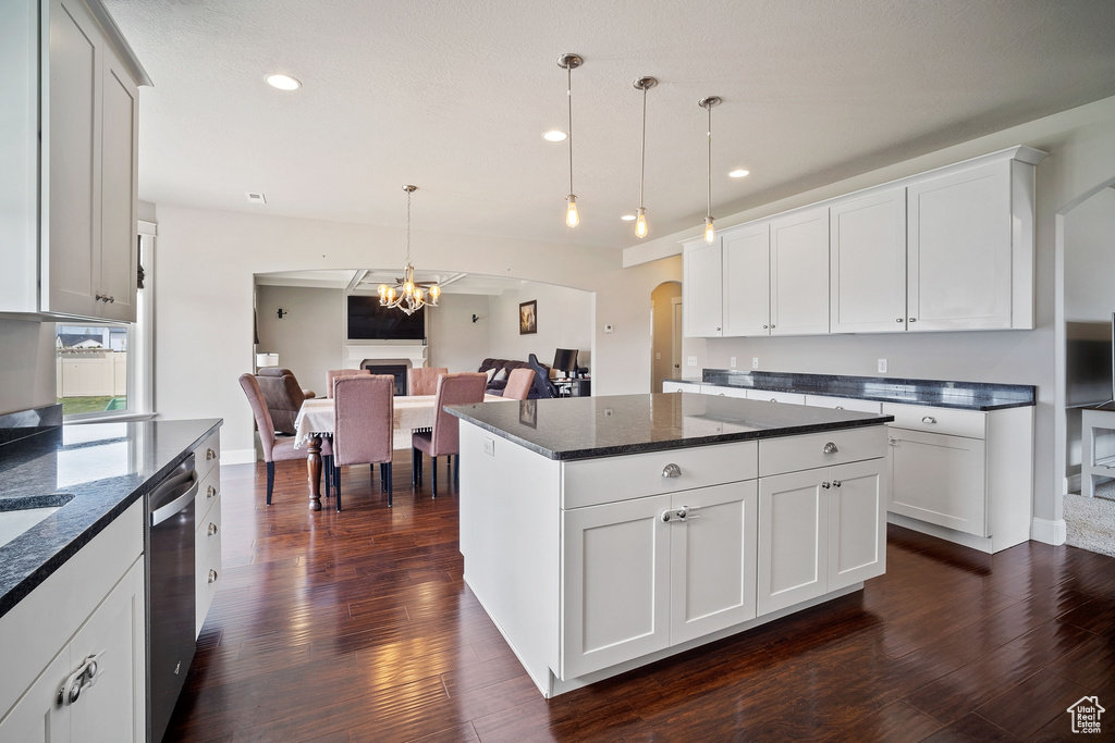 Kitchen featuring hanging light fixtures, white cabinets, dark hardwood / wood-style flooring, a center island, and a chandelier