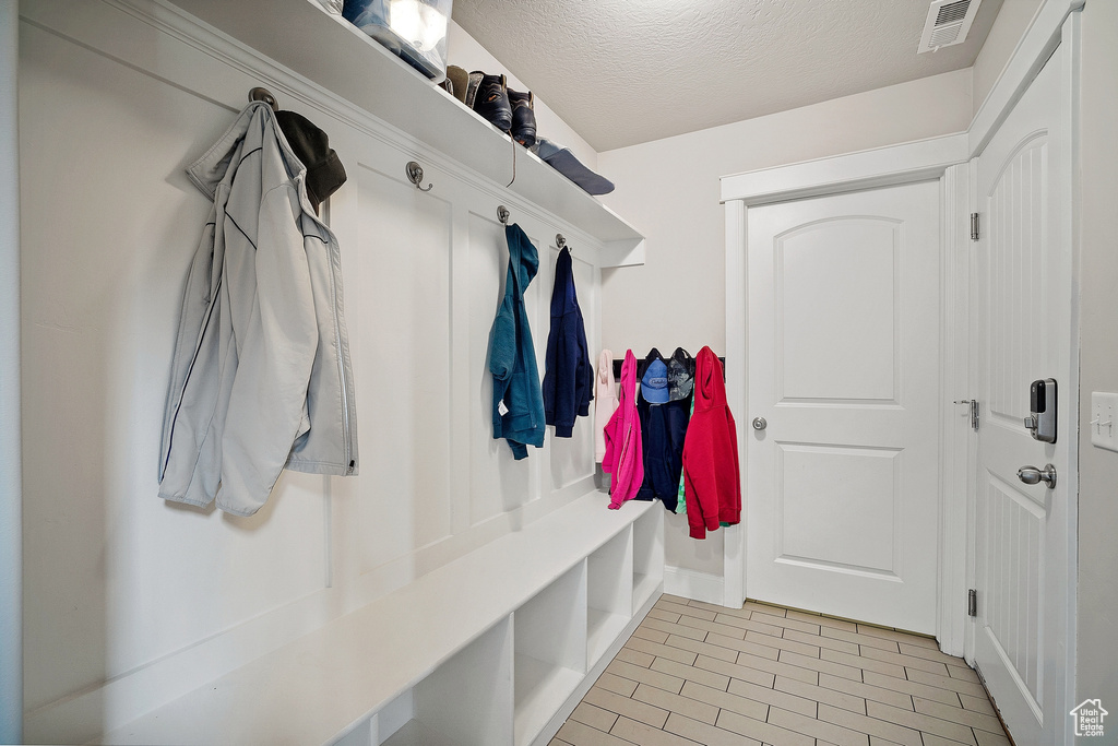 Mudroom with light tile floors and a textured ceiling