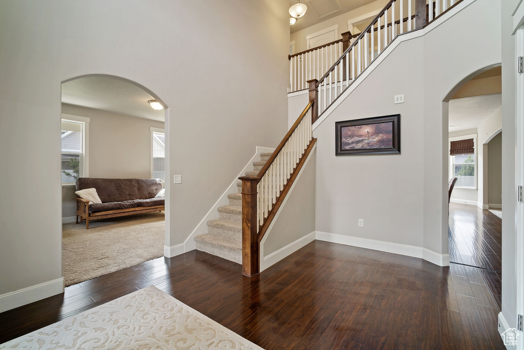 Staircase featuring dark hardwood / wood-style flooring and a high ceiling
