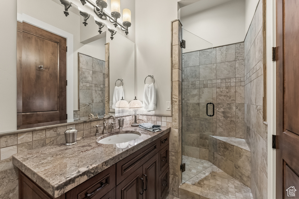 Bathroom featuring tile walls, tasteful backsplash, an enclosed shower, and vanity