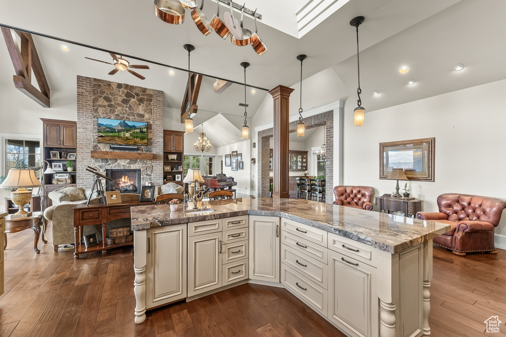 Kitchen featuring dark hardwood / wood-style flooring, decorative light fixtures, ceiling fan, and a fireplace