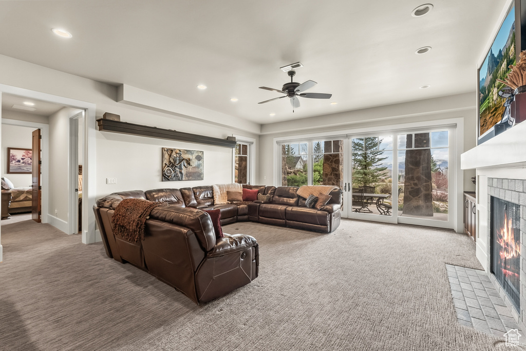 Living room with a fireplace, ceiling fan, and carpet flooring