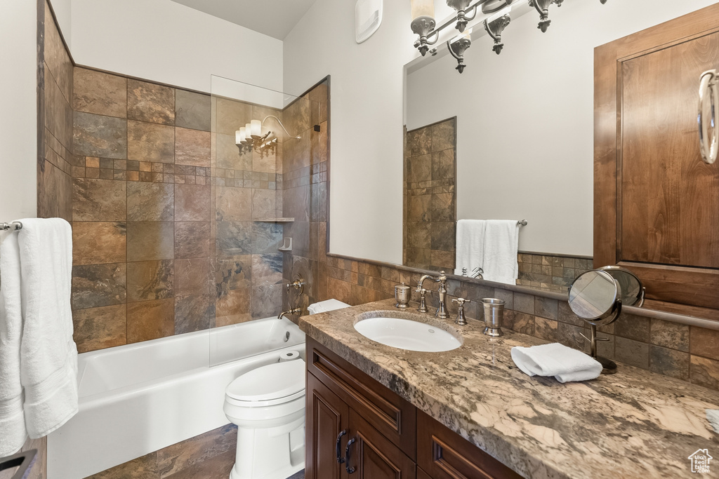 Full bathroom with vanity with extensive cabinet space, tiled shower / bath, and toilet