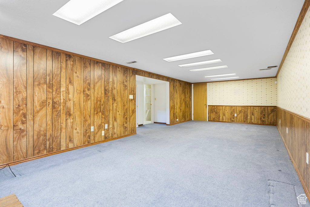 Carpeted spare room with wood walls