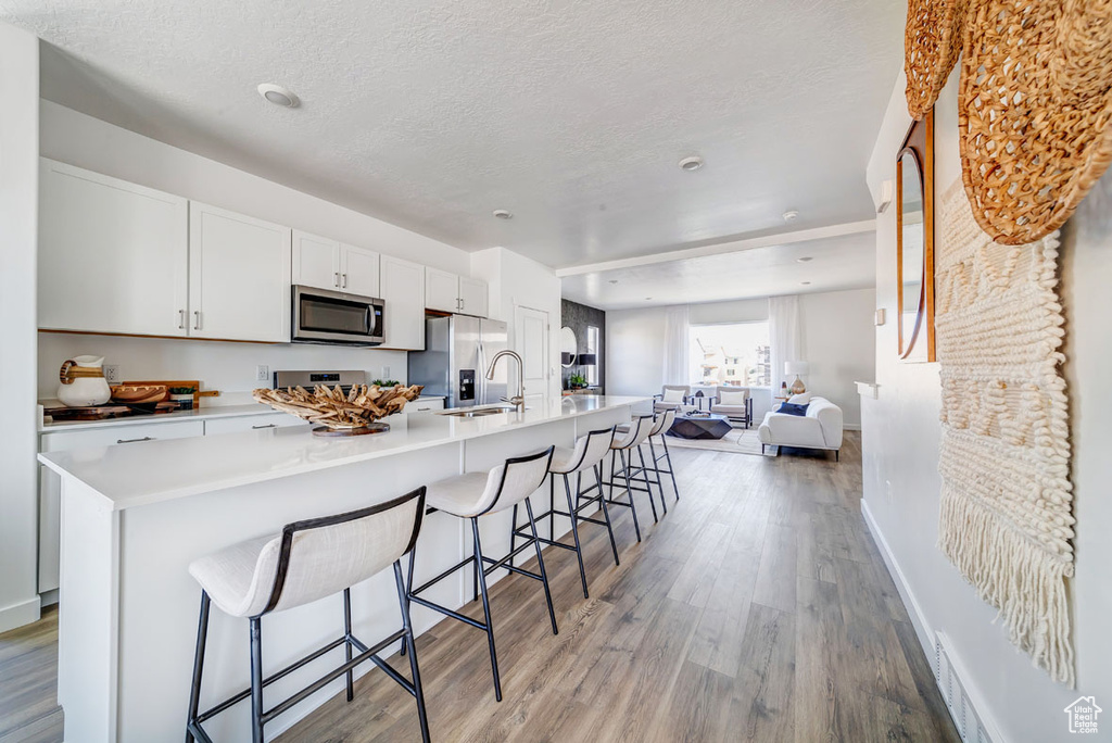 Kitchen featuring a textured ceiling, stainless steel appliances, and light hardwood / wood-style floors