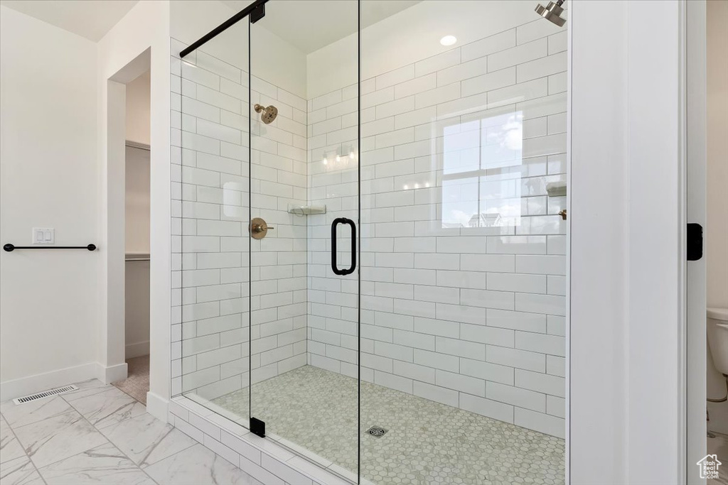 Bathroom with toilet, an enclosed shower, and tile floors