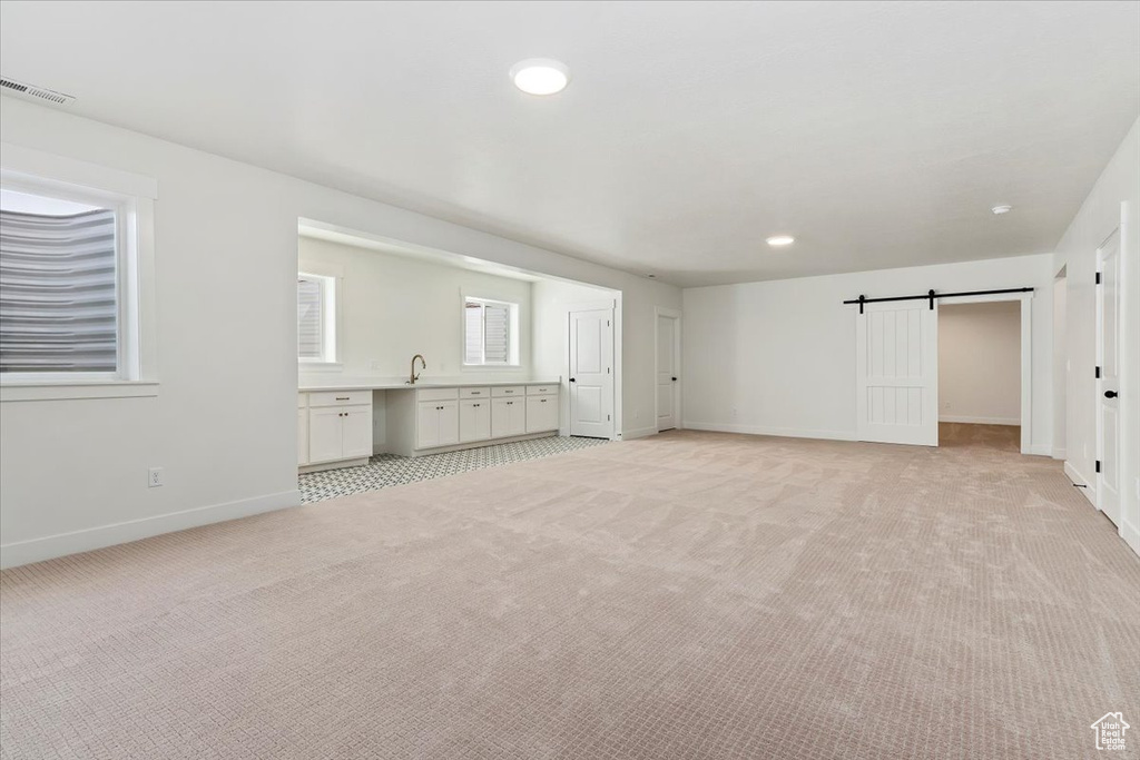 Unfurnished living room featuring light carpet and a barn door