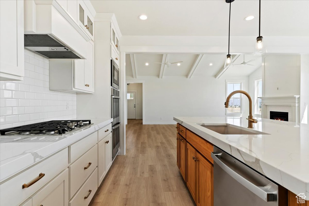 Kitchen featuring white cabinets, sink, tasteful backsplash, light hardwood / wood-style flooring, and premium range hood