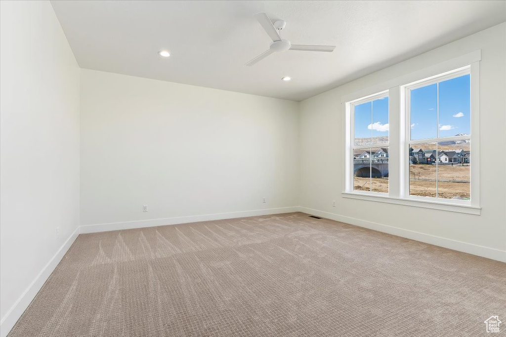Spare room featuring a wealth of natural light, ceiling fan, and carpet floors