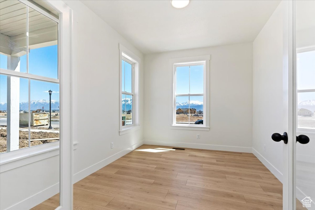 Empty room featuring a wealth of natural light, a mountain view, and light hardwood / wood-style floors