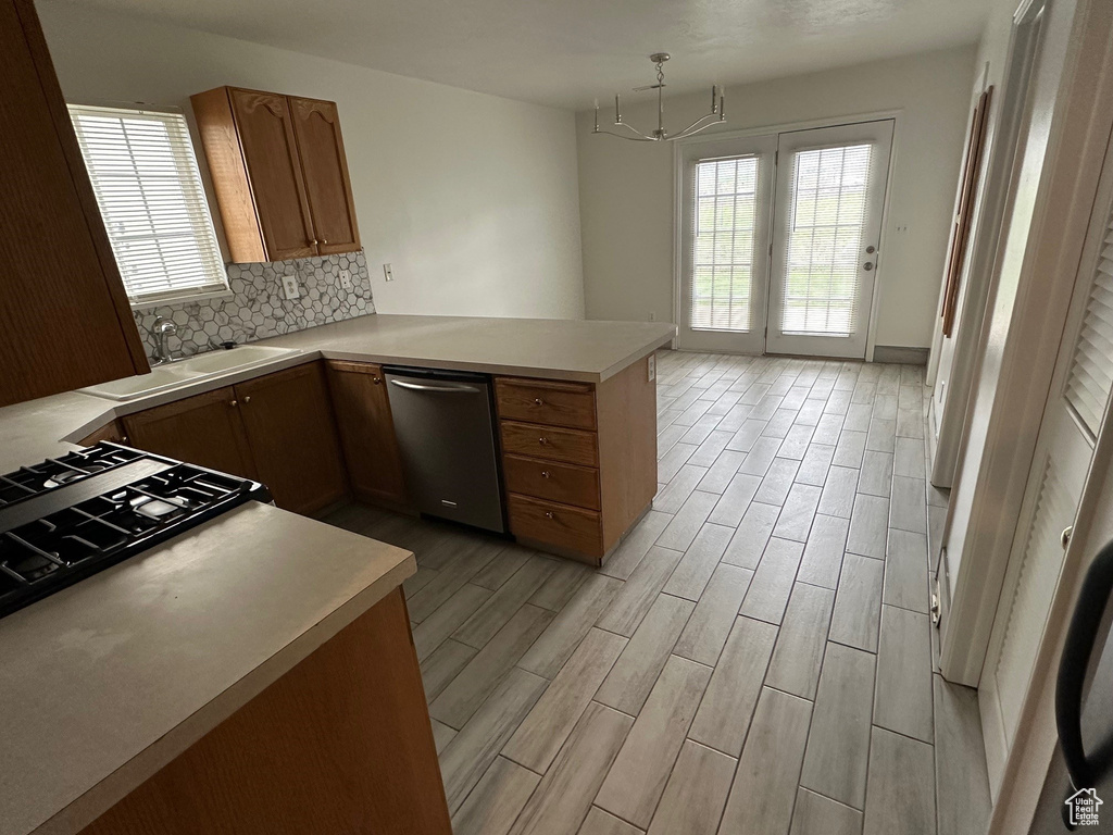 Kitchen featuring kitchen peninsula, backsplash, sink, light wood-type flooring, and stainless steel dishwasher