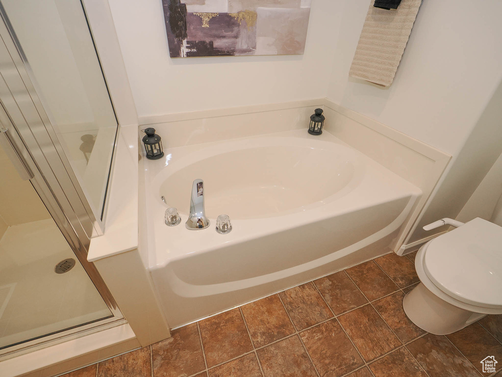 Bathroom featuring separate shower and tub, toilet, and tile flooring