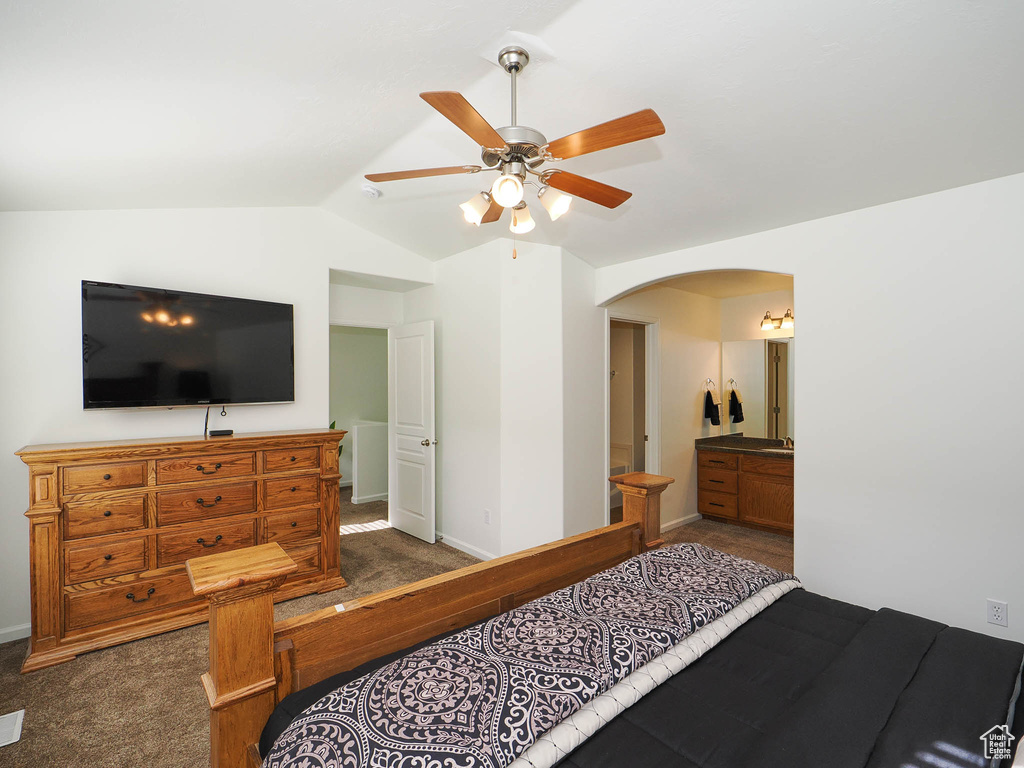 Carpeted bedroom with ensuite bath, ceiling fan, and vaulted ceiling