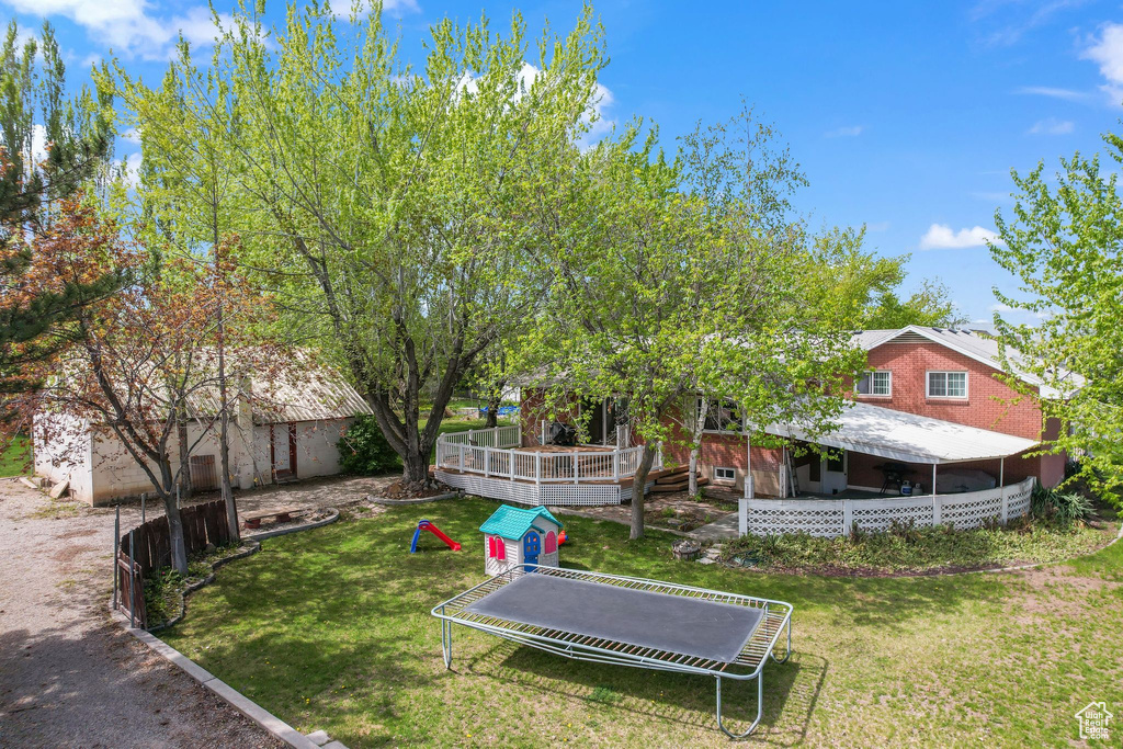 View of yard with a deck and a trampoline