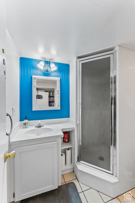 Bathroom with walk in shower, vanity with extensive cabinet space, and tile floors