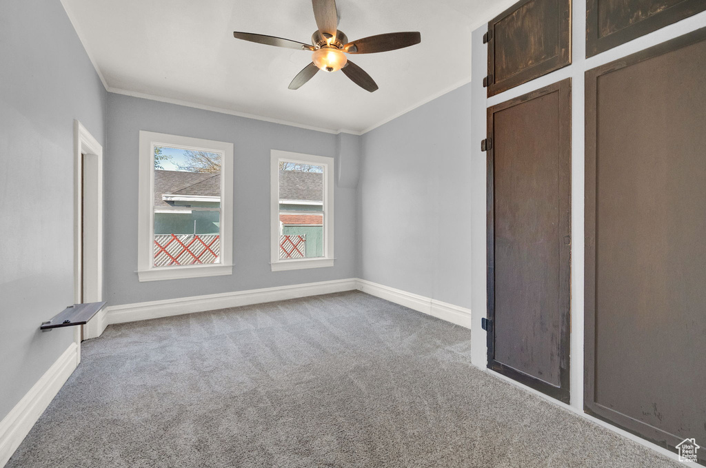 Carpeted spare room with ceiling fan and ornamental molding