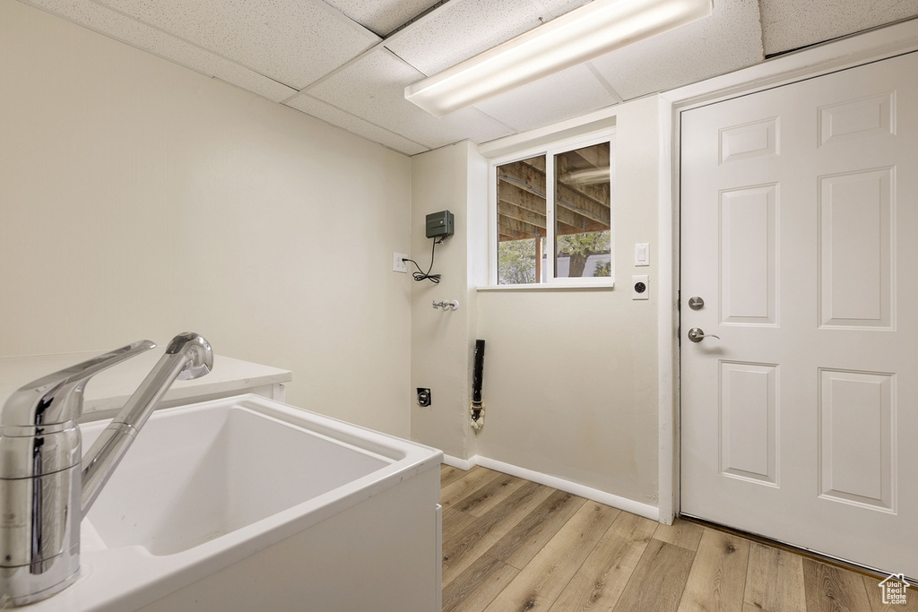 Clothes washing area featuring sink and light hardwood / wood-style flooring