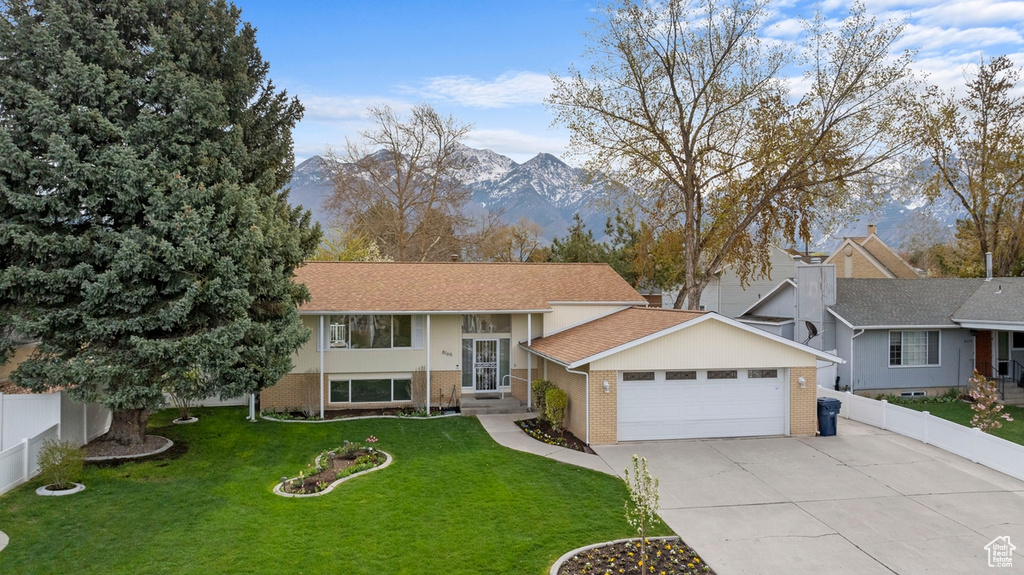 Bi-level home featuring a mountain view, a front lawn, and a garage