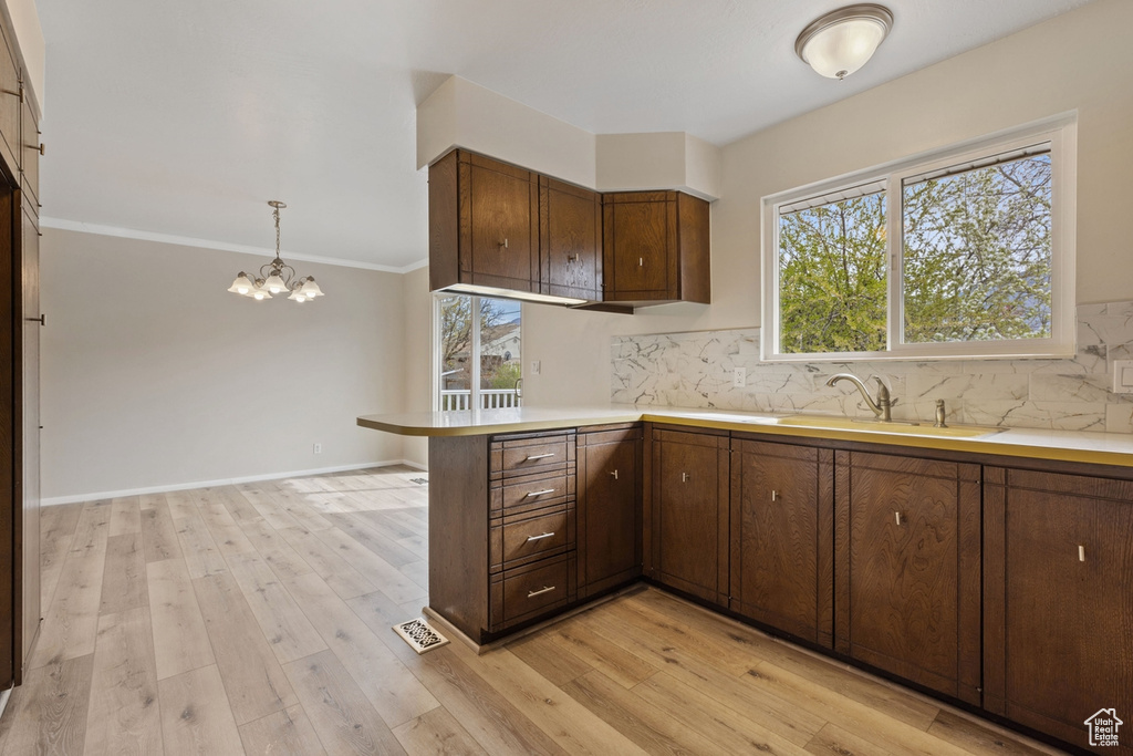 Kitchen featuring tasteful backsplash, decorative light fixtures, sink, and light wood-type flooring