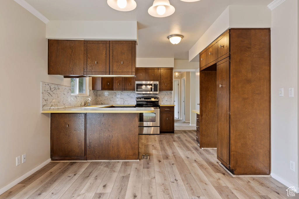 Kitchen featuring stainless steel appliances, kitchen peninsula, and light wood-type flooring