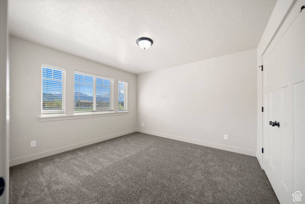 Empty room with a textured ceiling and carpet flooring