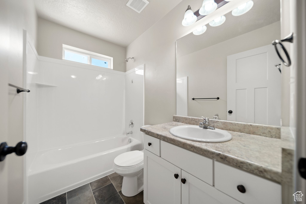 Full bathroom featuring shower / bathtub combination, toilet, a textured ceiling, vanity, and tile floors