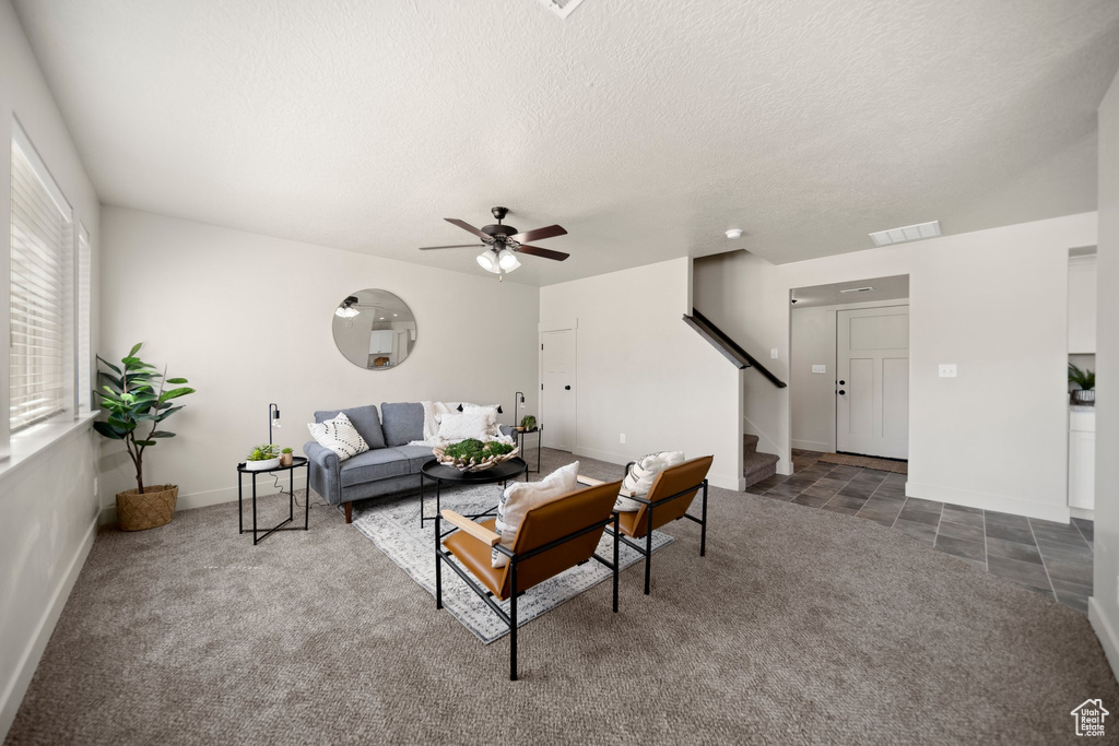 Carpeted living room featuring a textured ceiling and ceiling fan
