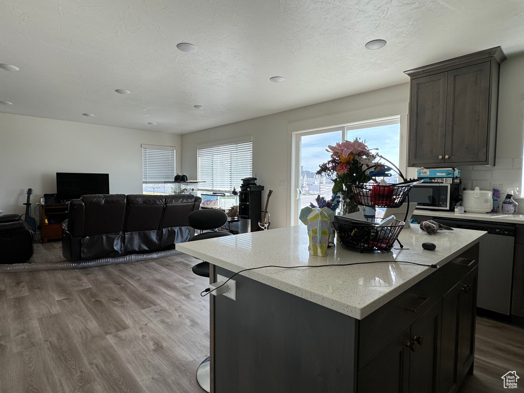 Kitchen featuring a center island, a healthy amount of sunlight, tasteful backsplash, and light wood-type flooring