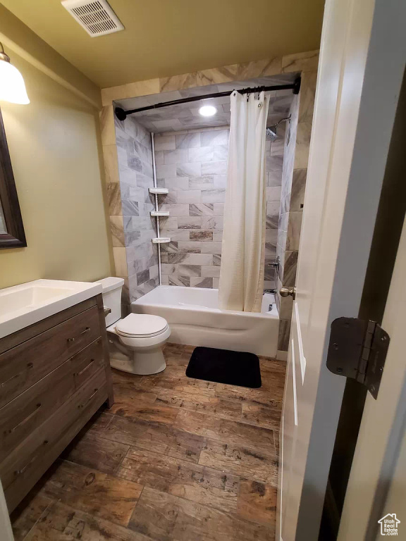 Full bathroom with hardwood / wood-style floors, shower / tub combo, vanity, and toilet