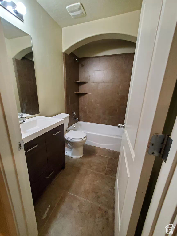 Full bathroom featuring tile flooring, vanity, tiled shower / bath combo, and toilet