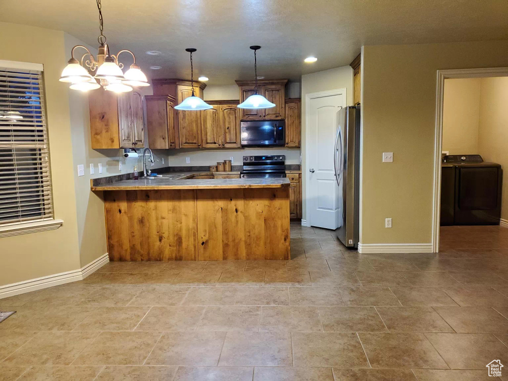 Kitchen featuring hanging light fixtures, washer / clothes dryer, tile flooring, range with electric stovetop, and stainless steel fridge