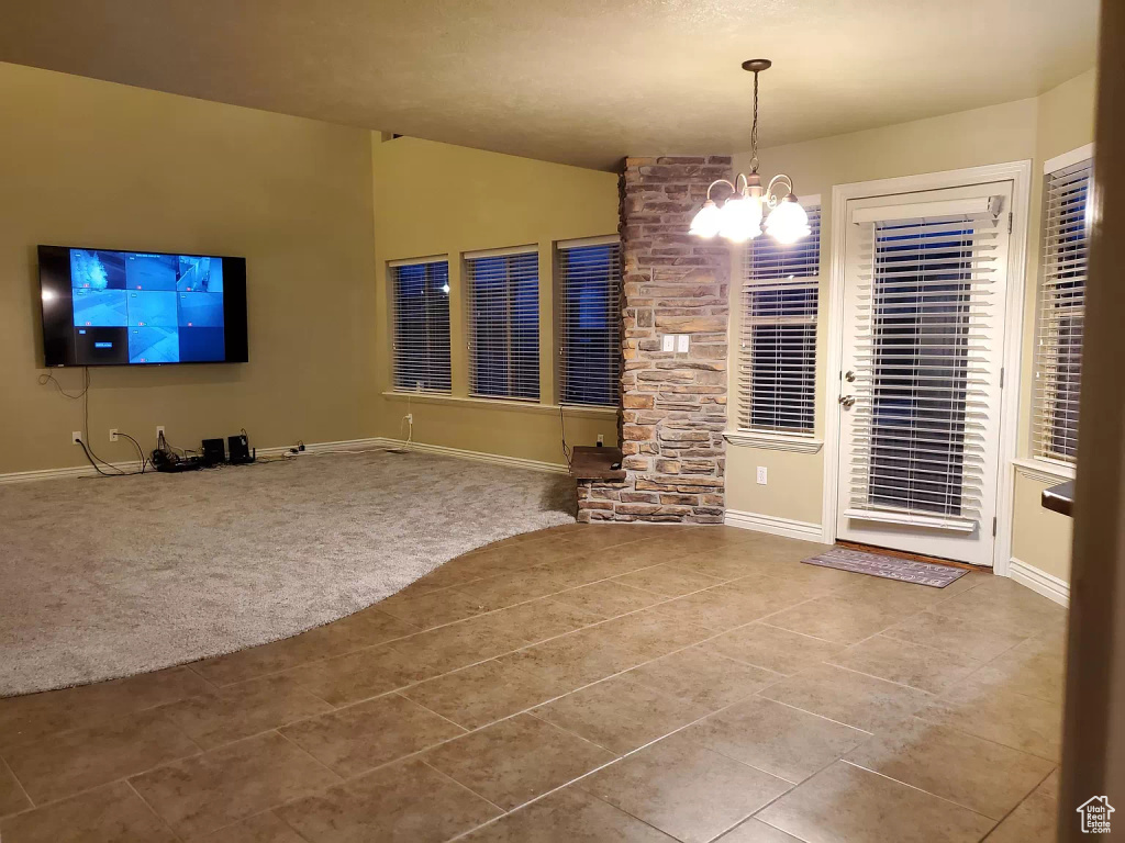 Unfurnished living room featuring tile floors and a notable chandelier