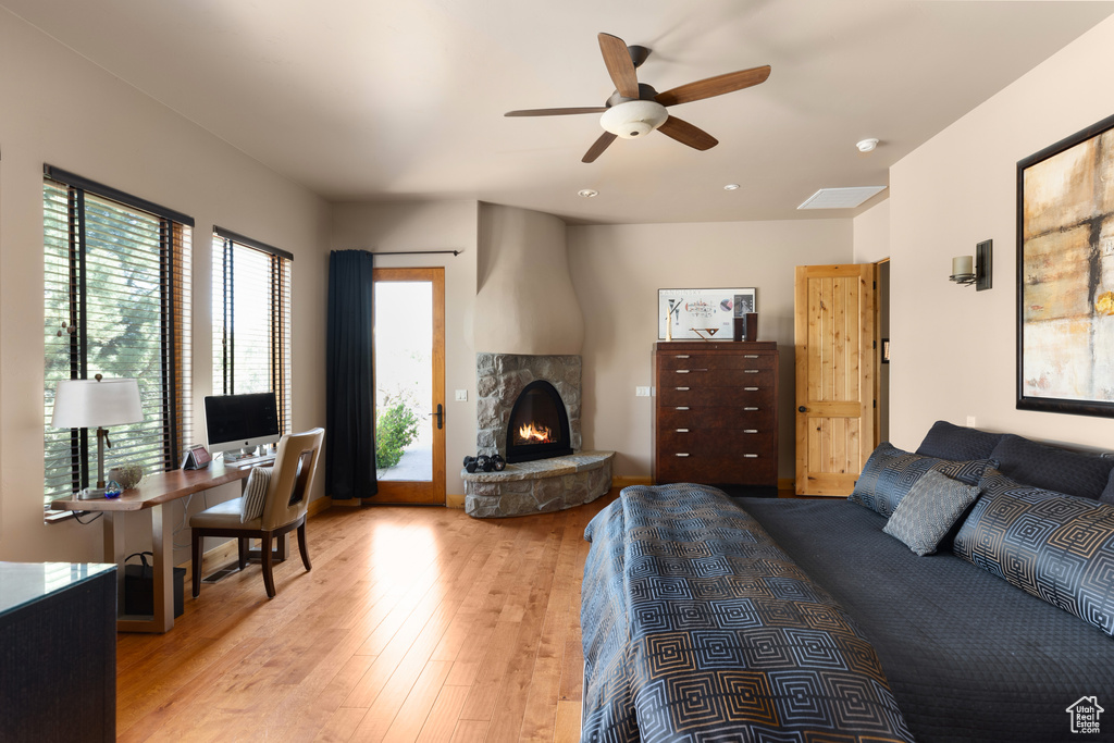 Bedroom with light hardwood / wood-style floors, ceiling fan, a fireplace, and access to exterior