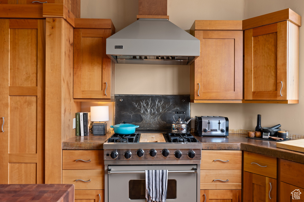 Kitchen featuring backsplash, wall chimney exhaust hood, and luxury range